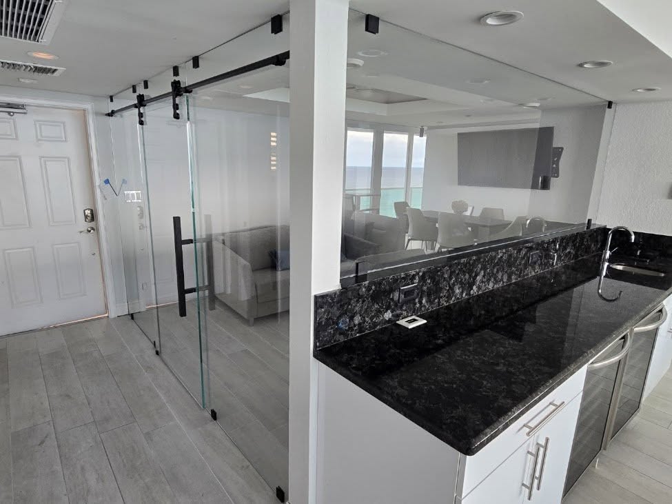 Sliding glass partition with track hardware in a condo