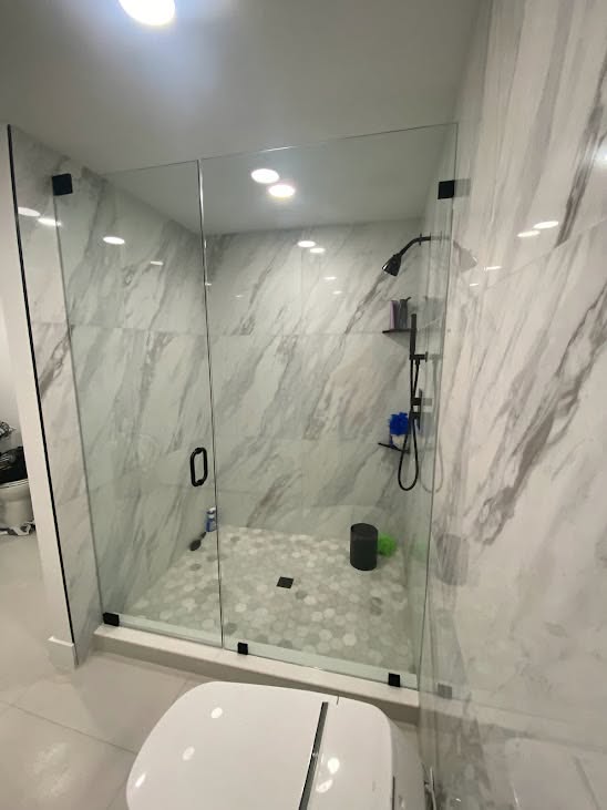 Frameless shower enclosure with marble tile and black hardware