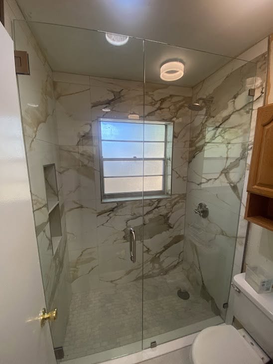 Frameless shower enclosure in marble with chrome hardware